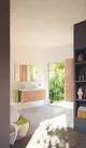 Moderne Badezimmeransicht mit einem Holzwaschtisch, Spiegeln und einer Ideal Standard Armatur. Der Raum hat große Fenster, die Tageslicht hereinlassen.